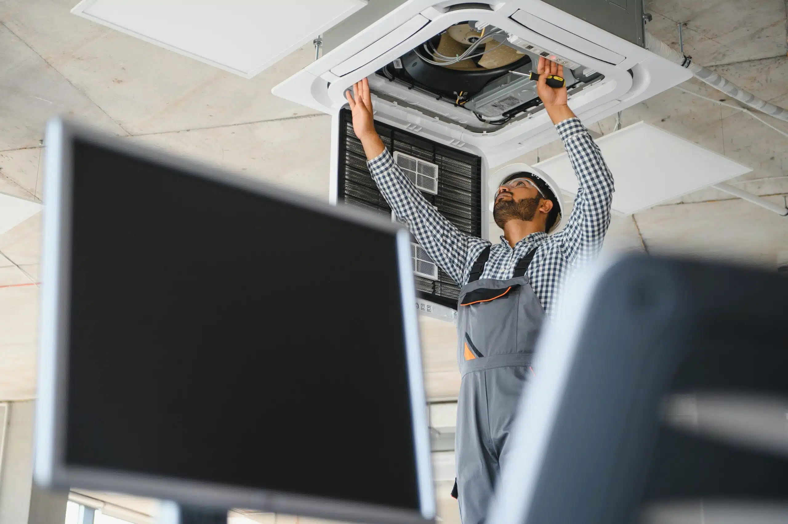 Professional technician maintaining modern air conditioner indoors